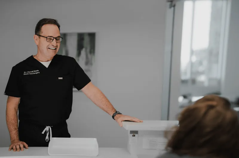 Dr. smiling at the front desk with a patient